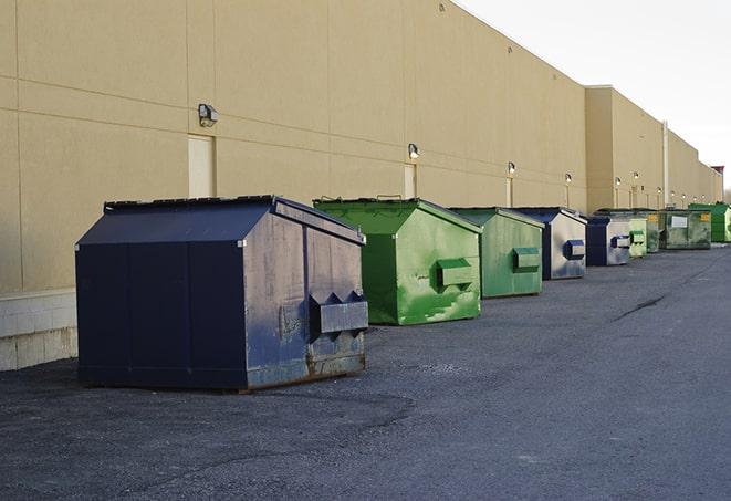 a construction worker unloading debris into a blue dumpster in Centerville TN